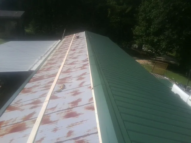 Old rusted panels beside newly installed green metal roofing — Wind Damage Roof Repair by Roofing Brothers in South Solon
