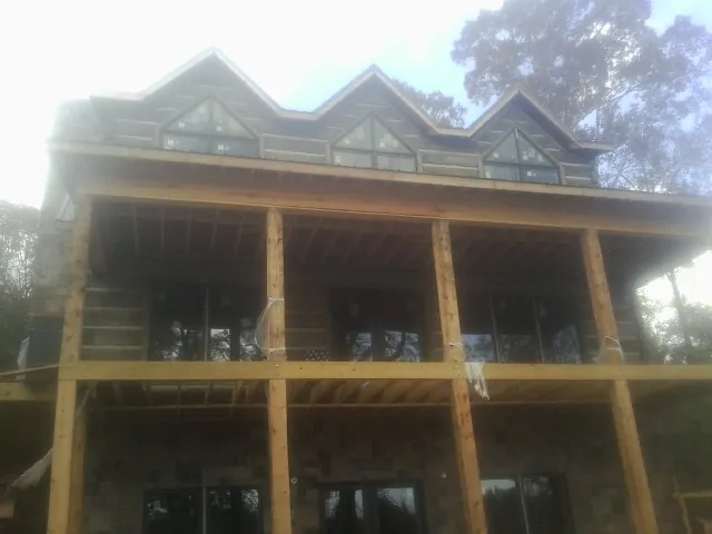 Dormers and porch framing on a large log home under construction — Roof Coating work by our crew in South Solon