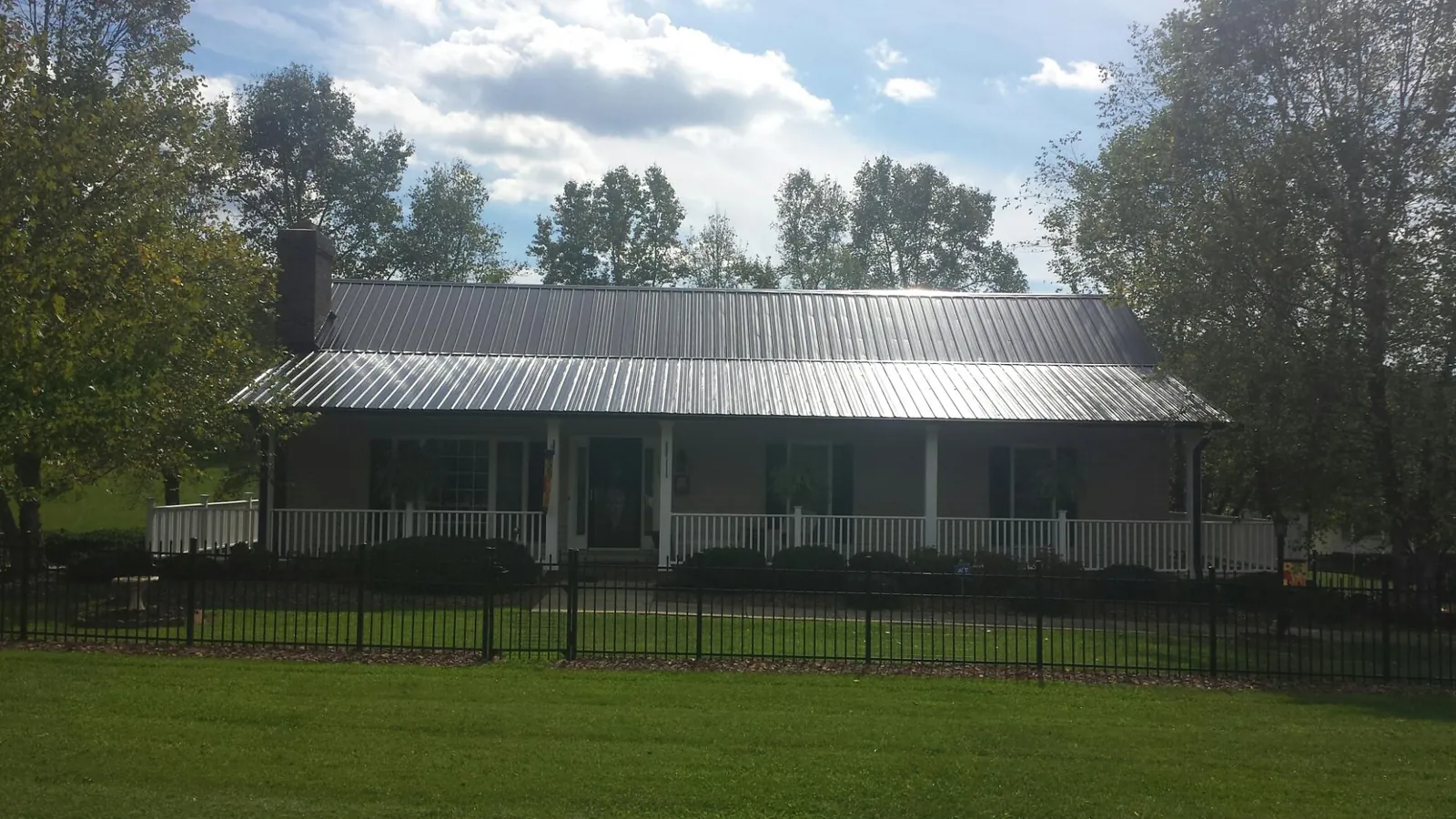 Gray metal roof on a brick ranch with a full width front porch — Gutter Guard Installation work by our crew in South Solon