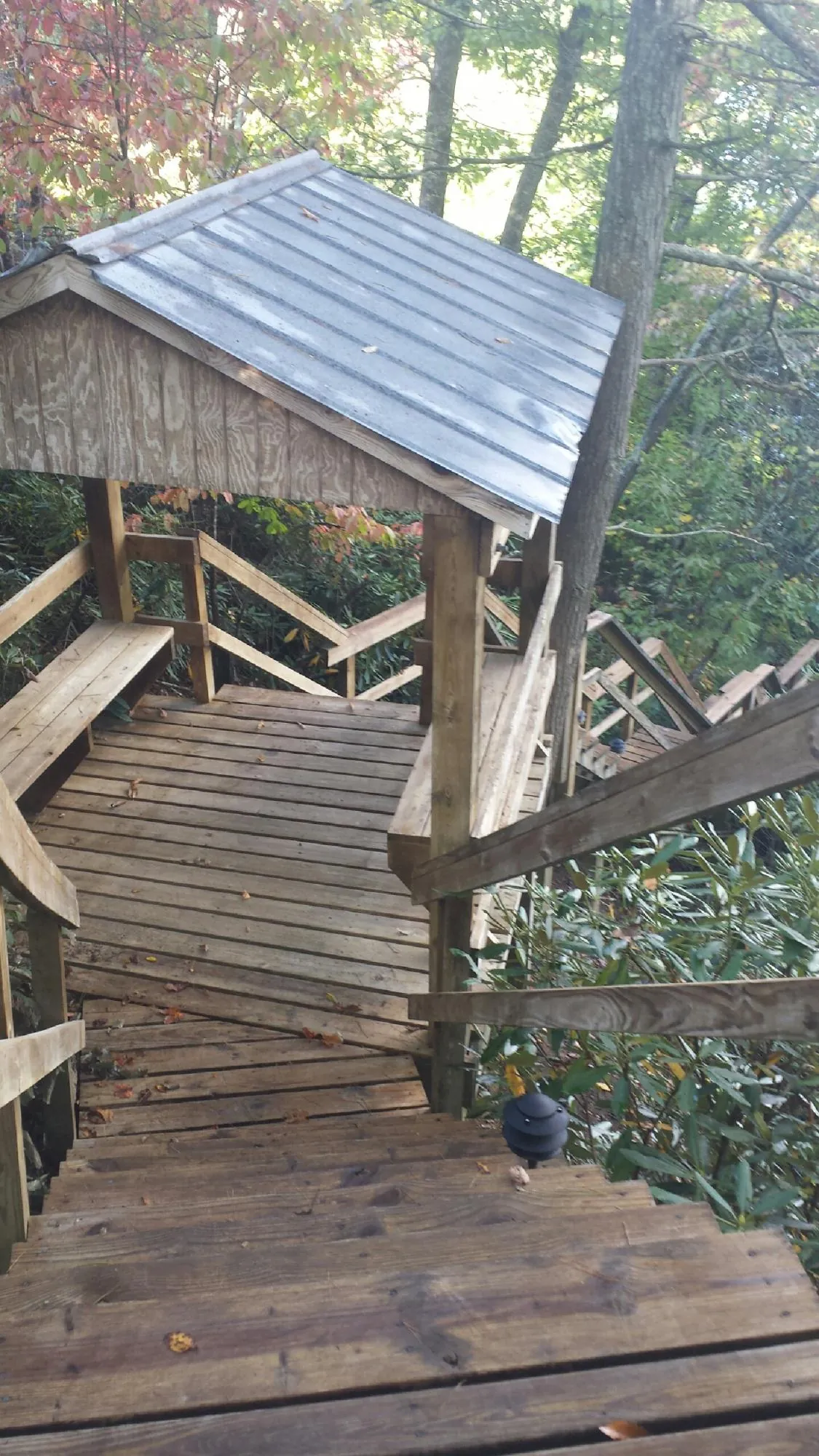 Metal roofed shelter over wooden steps on a wooded walkway — Skylight Repair & Installation work by our crew in South Solon