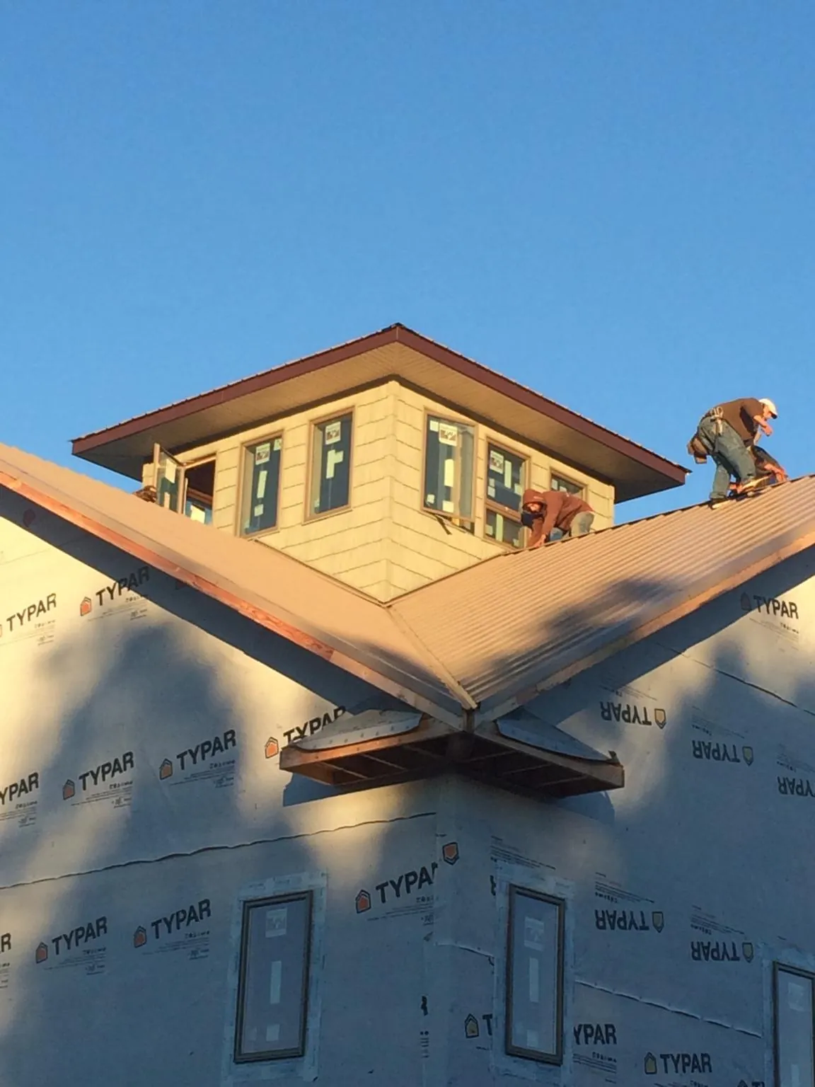 Roofers working around a rooftop cupola on a new metal roof at sunset — Roof Waterproofing in South Solon by Roofing Brothers